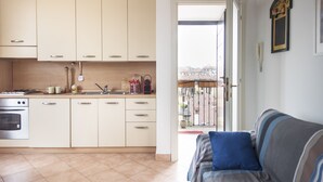 A modern kitchen with white cabinets, a built-in oven, and a window overlooking a balcony. - Typical Apartment on River Naviglio / Darsena (Milan)