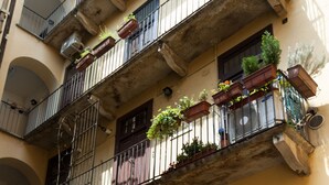 A multi-story building with balconies, some with plants. There are multiple windows and a visible staircase. - Typical Apartment on River Naviglio / Darsena (Milan)