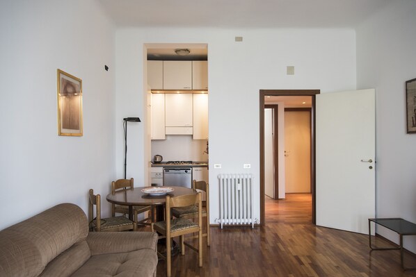 A compact living space with a dining area, kitchenette, and a door leading to another room.