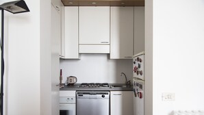 A compact kitchen with white cabinets, a dishwasher, a stove, and a refrigerator. - Bright & Cozy Flat near Navigli, Iulm, Tortona (Milan)