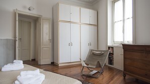 A bedroom with a bed, a chair, a wardrobe, and a dresser.