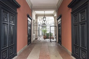 A corridor with black ornate doors and a wrought iron gate leading to a courtyard. - Pleasant 2 Bedrooms Flat in Brera (Milan)
