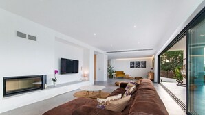 Una sala de estar moderna con un sofá marrón, un televisor de pantalla plana y una chimenea.