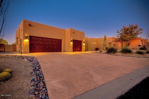 A modern house with a large garage, a well-maintained driveway, and desert landscaping. - Troon North Beautiful Home on the Golf Course! (Scottsdale)