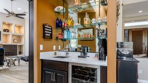 Cocina moderna con barra, que incluye un botellero, diferentes botellas y una cafetera.