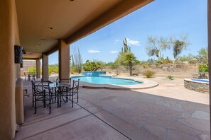 An outdoor patio with a pool, surrounded by desert vegetation and a stone wall. - Troon North Beautiful Home on the Golf Course! (Scottsdale)