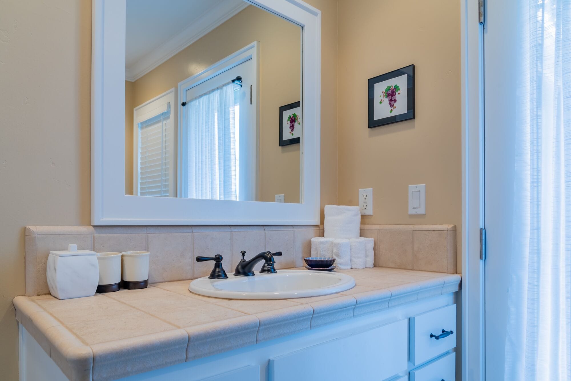 Une salle de bain avec un grand miroir, un lavabo, un porte-serviettes et des toilettes.