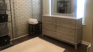 Een badkamer met een bakstenen muur, een wastafel met lades, een spiegel en een witte vloerkleed.
