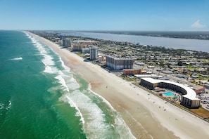 An aerial view of a coastal area with a beach, ocean, and a hotel complex with a pool and outdoor seating area. - Fabulous Ocean Views at Daytona Beach! (Daytona beach shores)