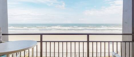 A balcony with a view of the beach and ocean.