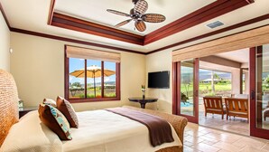 Quarto com cama grande, ventilador de teto, televisão e vista para o exterior.