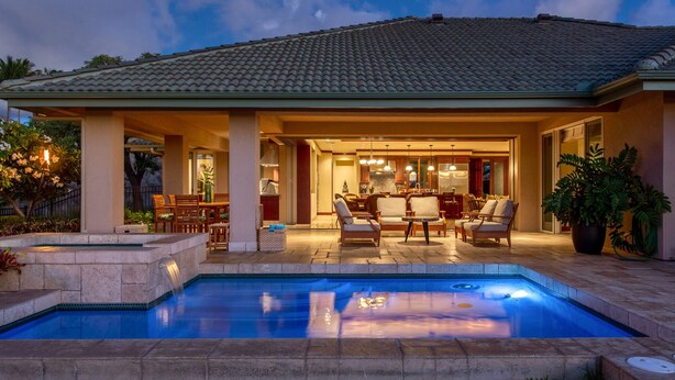 Uma casa com piscina, móveis de exterior e varanda coberta.