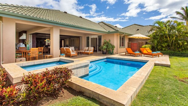 Una casa moderna con piscina, mobiliario exterior y un porche cubierto.