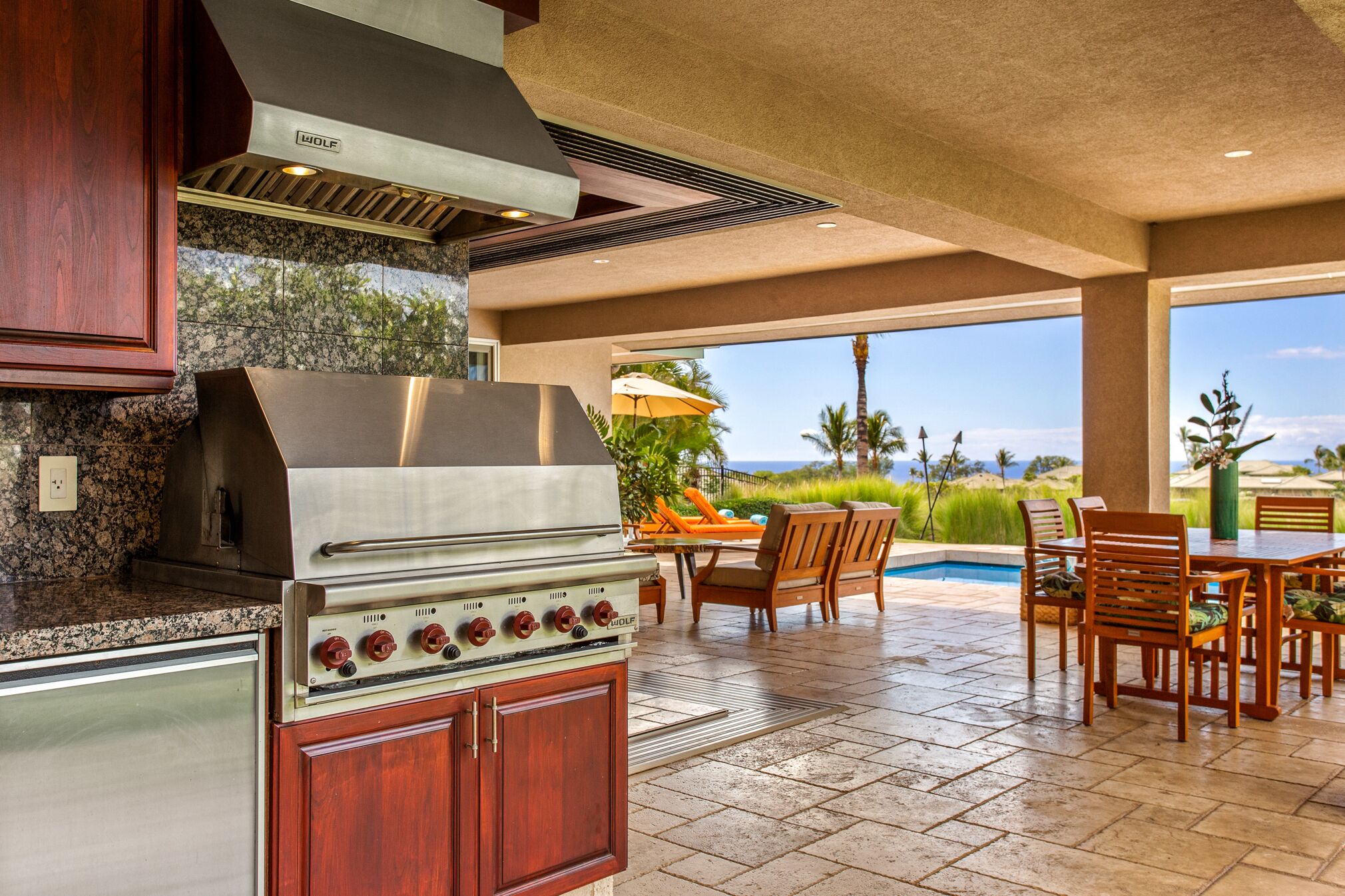 A kitchen with a built-in grill, granite countertops, and wooden cabinets.