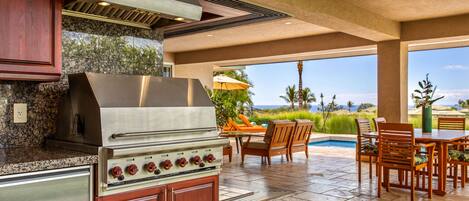 A kitchen with a built-in grill, granite countertops, and wooden cabinets.