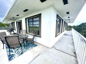 Eine überdachte Terrasse im Freien mit Tisch, Stühlen, einem Grill und Blick auf die Landschaft.
