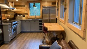Una cucina accogliente con travi in legno, un frigorifero in acciaio inossidabile e un divano in pelle con un cuscino blu.