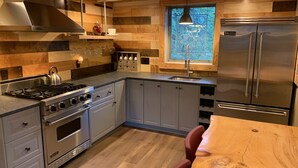 Una cucina moderna con piano cottura a gas, forno, frigorifero in acciaio inox e dettagli in legno.