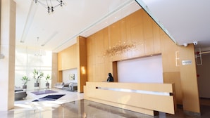 A modern reception area with a wooden reception desk, a receptionist, and a reception sign. - Heaven Prestige Hotel (Kfar Yassine)