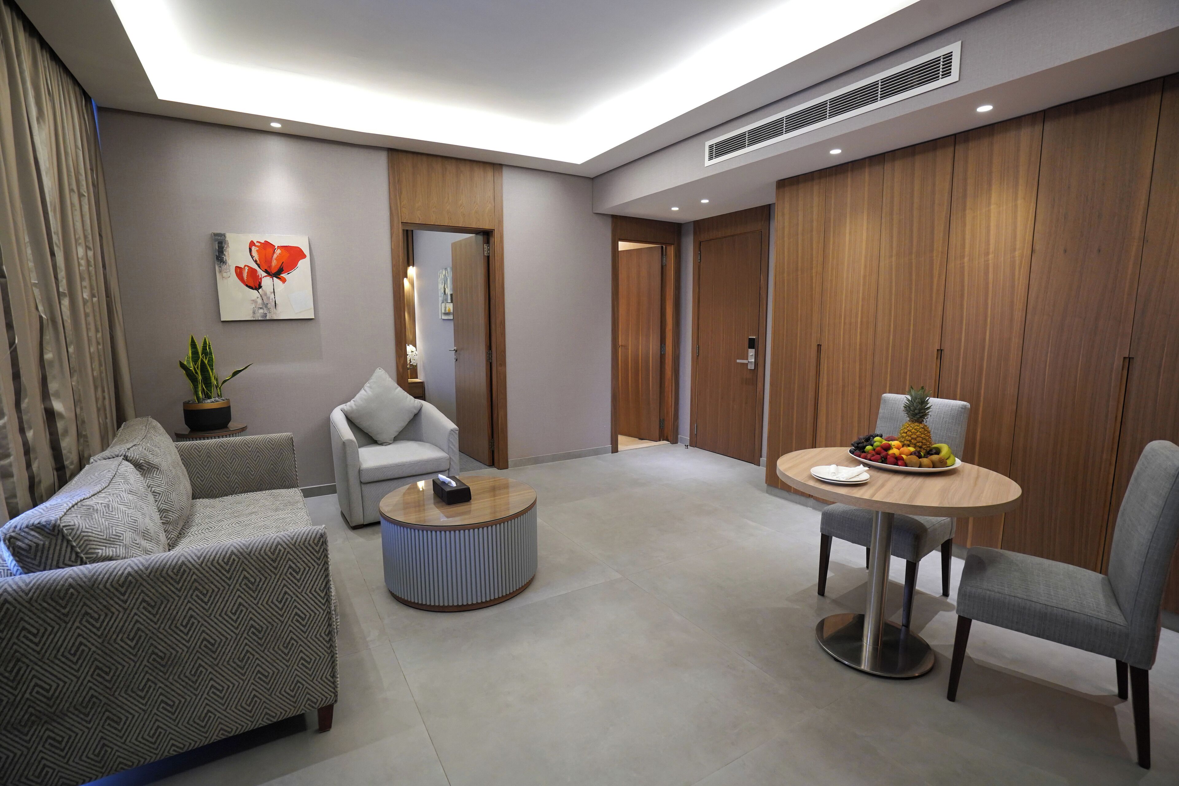 Uma sala de estar moderna com sofá, poltrona, mesa de centro e mesa de jantar com frutas.
