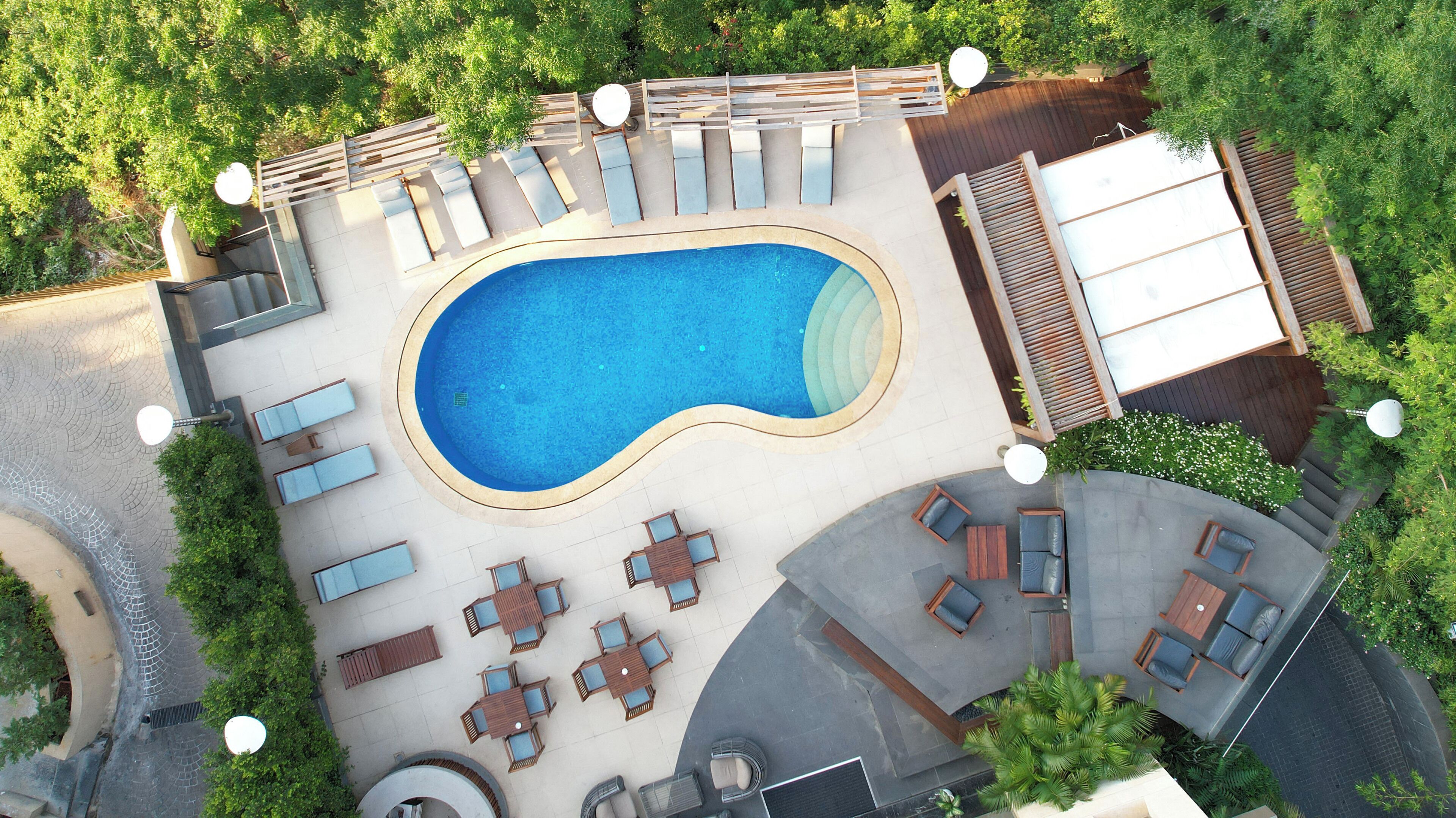 Vista aérea de un complejo turístico con piscina, zonas de estar al aire libre y un porche cubierto.