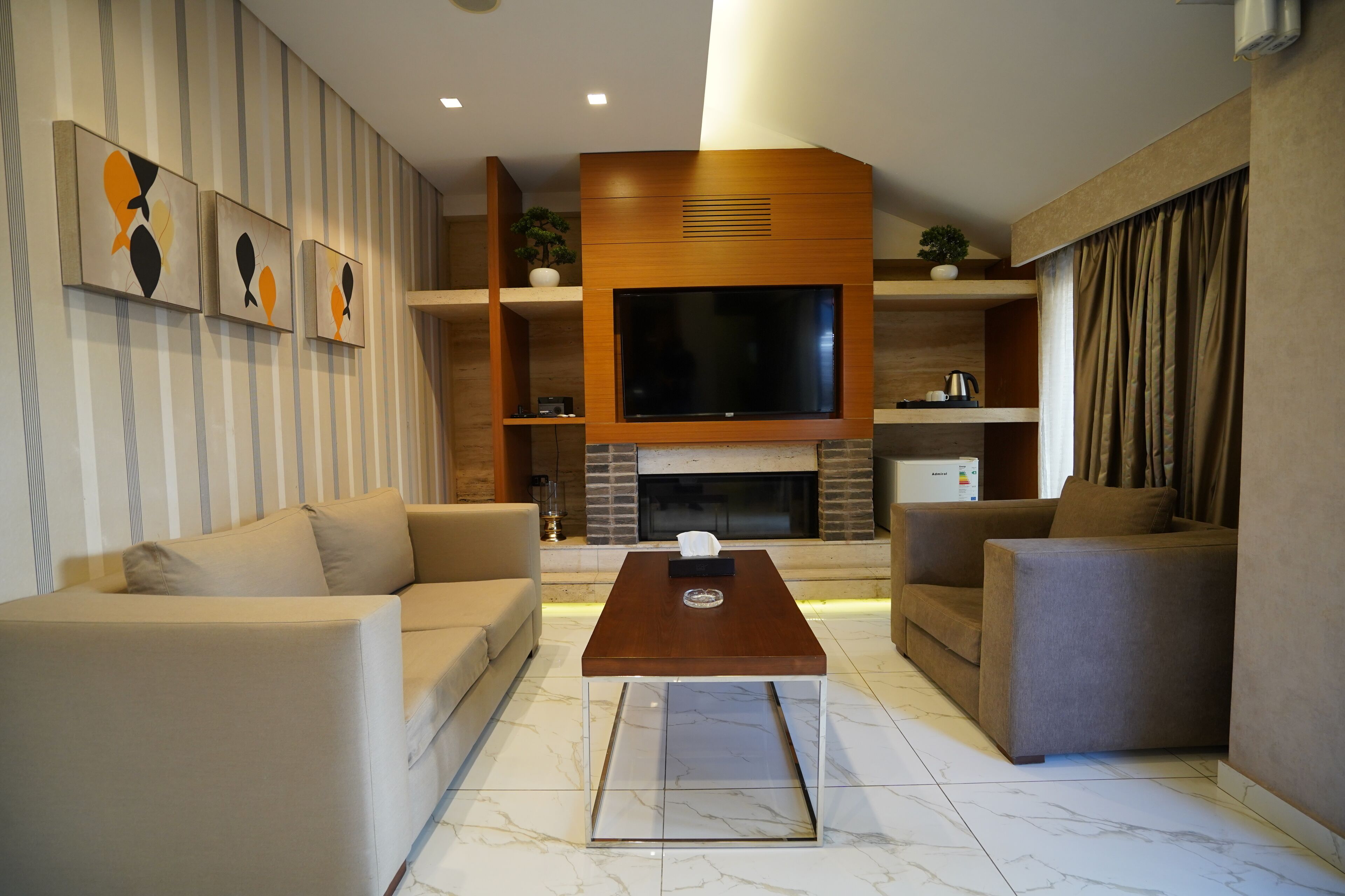 Una sala de estar moderna con un televisor de pantalla plana grande, dos sofás, una mesa de centro y una chimenea.