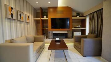 Una sala de estar moderna con un televisor de pantalla plana grande, dos sofás, una mesa de centro y una chimenea.
