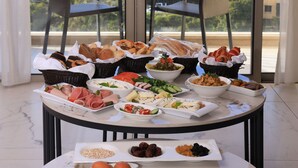 A table with various food items and two chairs facing a view of the sea. - Heaven Prestige Hotel (Kfar Yassine)