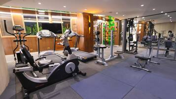 Un gimnasio con diversos equipos de ejercicio, incluyendo cintas de correr, una elíptica y máquinas de pesas.