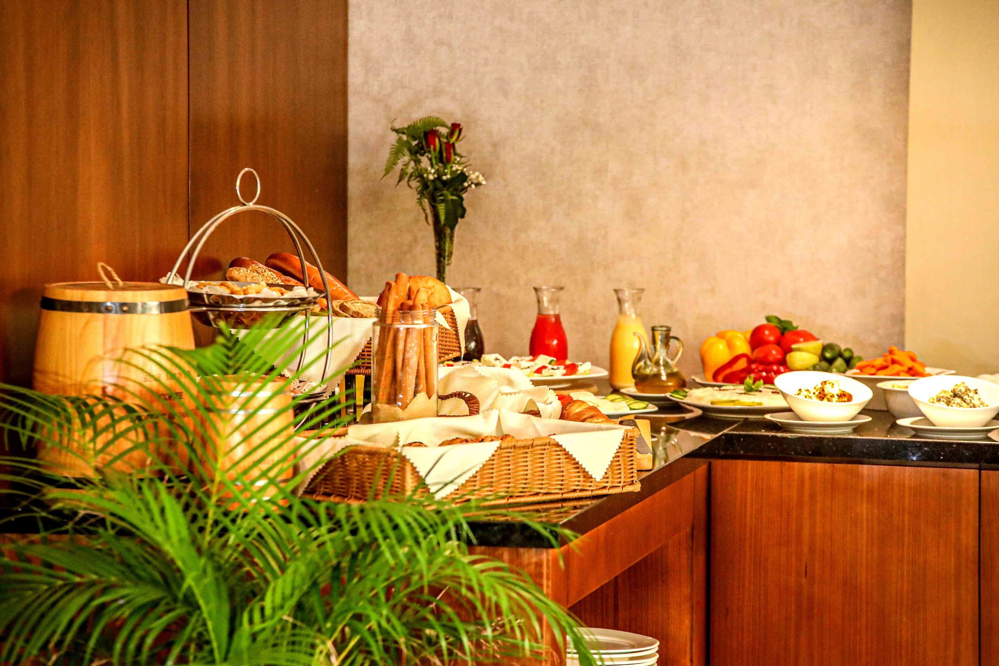 A buffet setup with various food items, including fruits, vegetables, and bread.