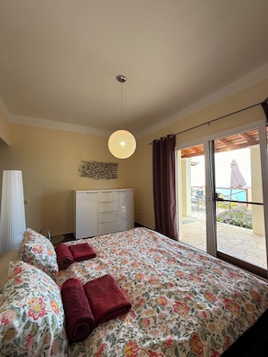 Un dormitorio con cama, armario, lámpara colgante y vistas al exterior.