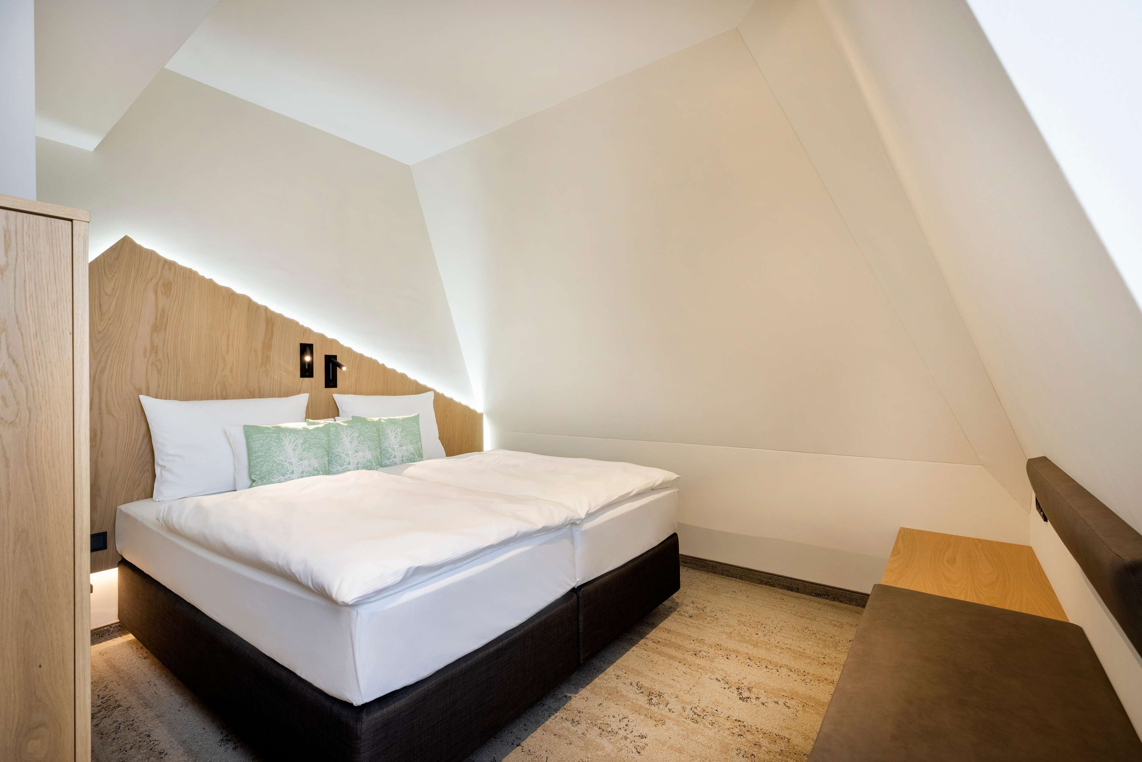 Um quarto moderno com cama beliche, cabeceira de madeira e um pequeno banco de madeira.