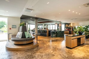Un vestíbulo moderno con zona de estar, mostrador de recepción y bar.