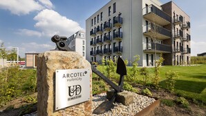 A modern hotel with a sign indicating it is part of the UDB network, featuring a unique anchor sculpture in the foreground. - ARCOTEL HafenCity Dresden (Dresden)