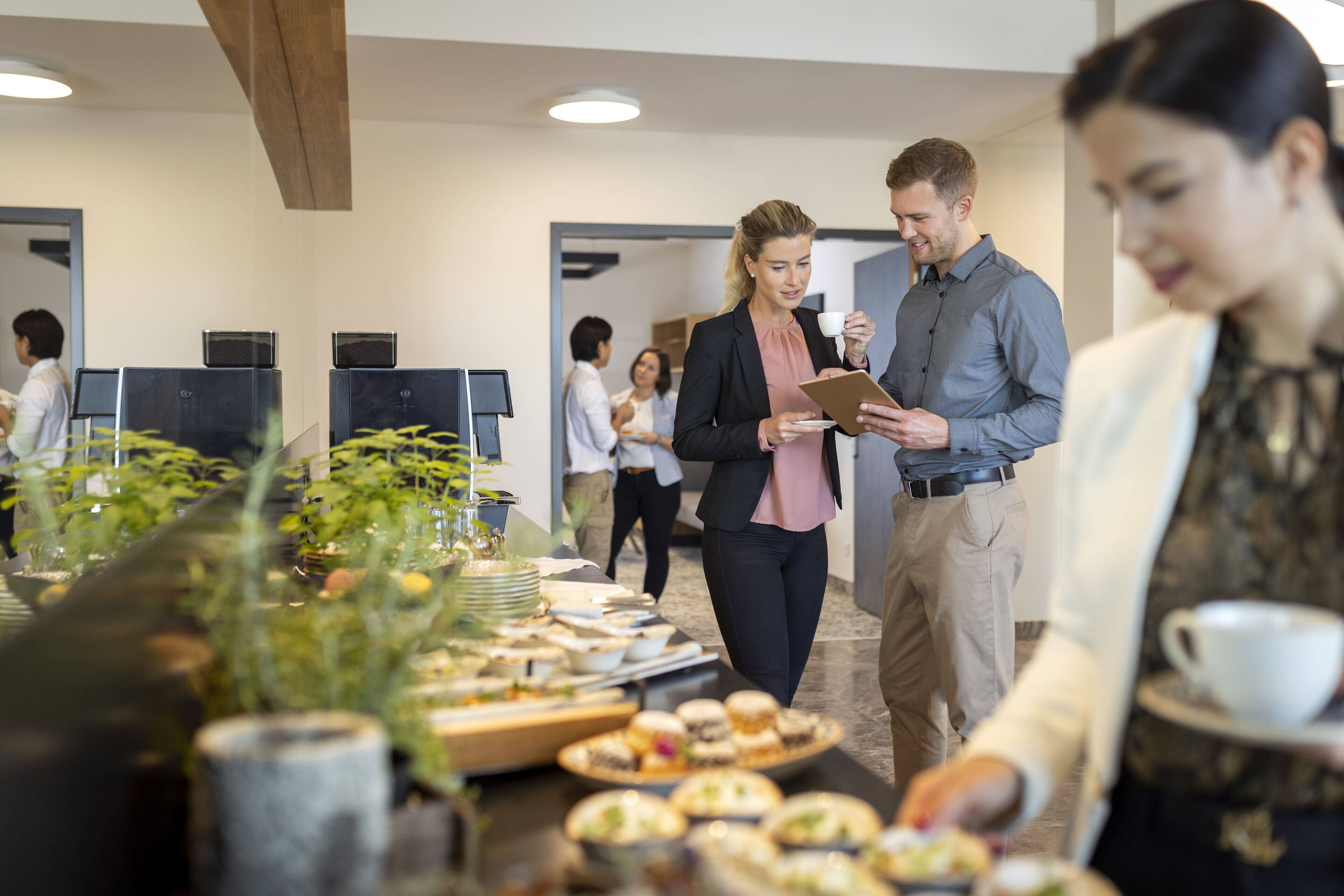 Ein Konferenzraum mit einem Buffet, mehreren Arbeitsplätzen und einem modernen Deckenstil.