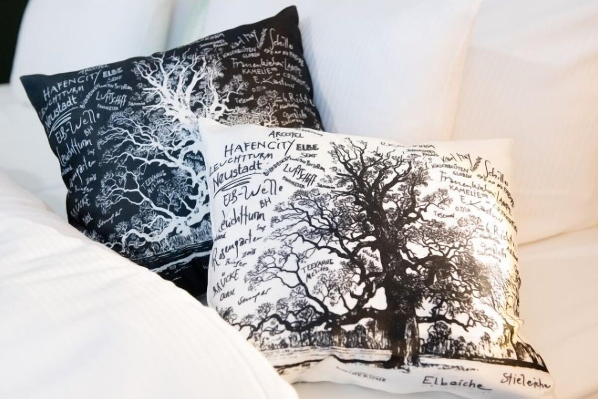 Two pillows with tree designs and text on a white couch.