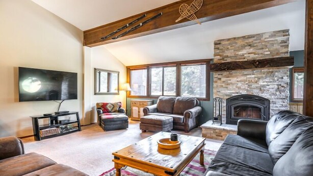 Una sala de estar acogedora con chimenea, sofás de cuero y una televisión.