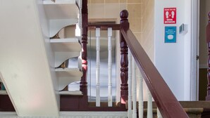 A staircase with a wooden handrail and white balusters, leading to an elevator.
