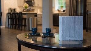 A modern kitchen with a glass-top table displaying two blue cups and a box labeled "Росно Дреамс".