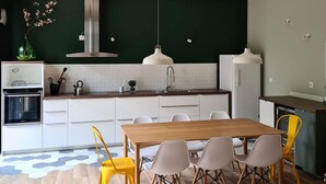 Una cocina moderna con una isla central, armarios blancos y un comedor con mesa y sillas de madera.