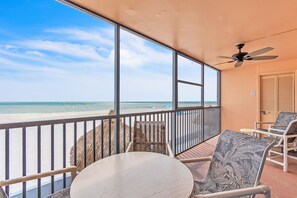 Ein Balkon mit Blick auf den Strand, ein Deckenventilator und ein Tisch mit Stühlen.