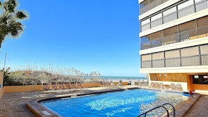 A swimming pool with lounge chairs and a view of the ocean.