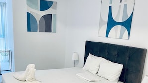 Habitación de hotel con una cama grande, una mesita de noche, una lámpara y arte abstracto en la pared.