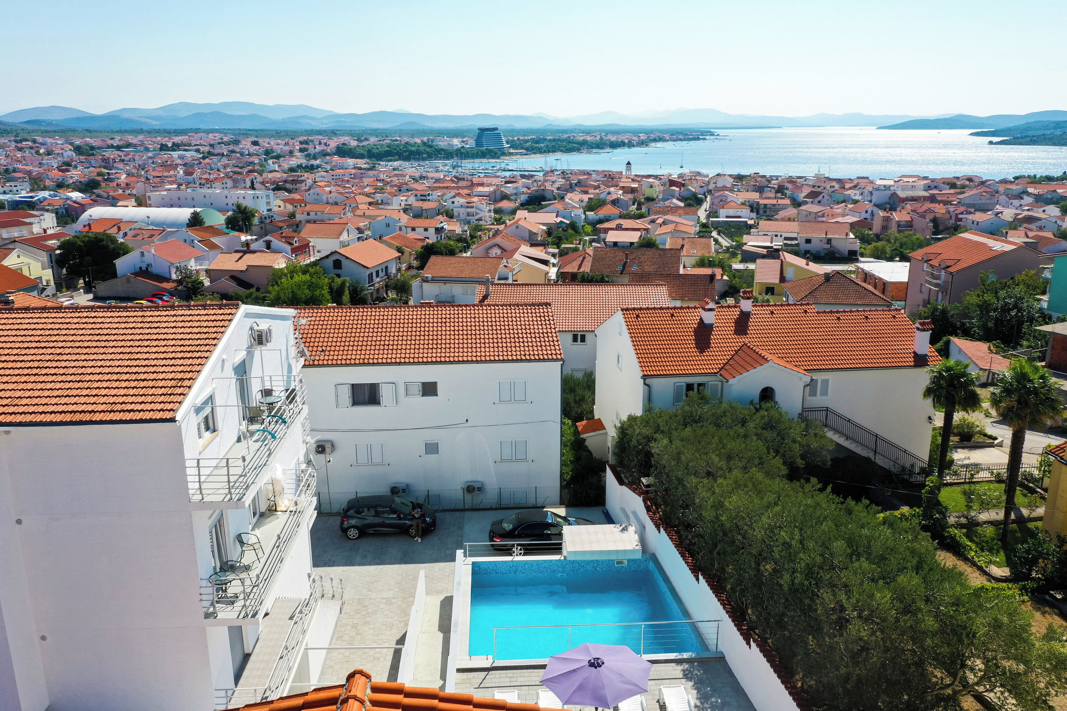 Uma  área residencial com piscina, edifícios brancos e telhados em telha vermelha.
