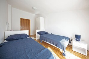 Une chambre avec deux lits, une armoire, une table de chevet avec une lampe et un plancher en bois.