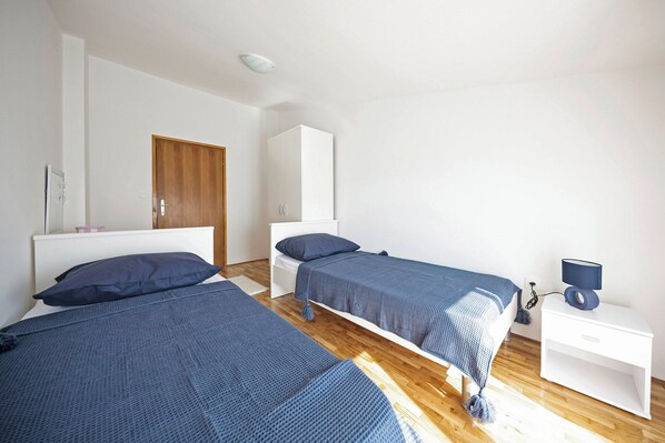 Une chambre avec deux lits, une armoire, une table de chevet avec une lampe et un plancher en bois.