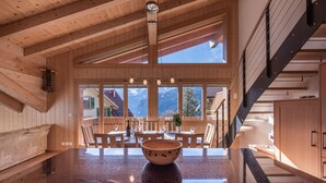 Interior de madera con un amplio ventanal, una isla central con un cuenco y una escalera.