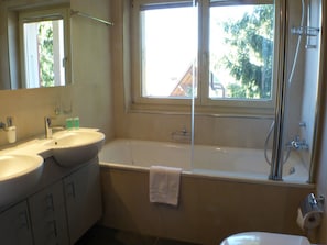 Casa de banho com duas pias, uma banheira e um chuveiro.