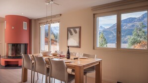 A dining area with a wooden table, chairs, and a fireplace. - Chalet Brunner 4 (Lauterbrunnen)