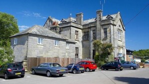 A stone building with multiple windows and a pitched roof. - Caravan Nearby Hastings, Coghurst Hall Park (Hastings)